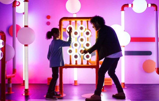 A man and a girl playing with an interactive display in a museum